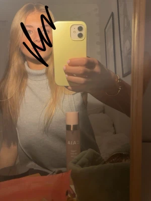 Ljusgrå ärmlös polotopp - Snygg ljusgrå polotopp i ärmlös modell. Perfekt att styla med jeans eller kjol för en trendig look. Mjuk och bekväm med hög krage som ger en stilren känsla.