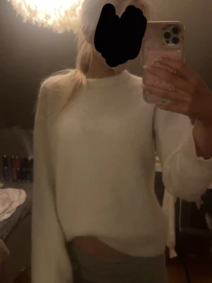 Vit fluffig stickad tröja bikbok  - Mysig vit stickad tröja med fluffig känsla och rund hals. Tröjan har en avslappnad passform och långa ärmar, perfekt för att hålla värmen under kyliga dagar. Enkel och stilren design som passar till det mesta.