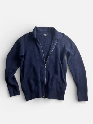 Mörkblå ziptröja (Massimo Dutti)  - Säljer en mörkblå stickad Massimo Dutti ziptröja med krage. Tröjan har hel dragkedja framtill och ribbade muddar vid ärmslut och nederkant. Perfekt för lager-på-lager och enkel att matcha med jeans eller t-shirt.