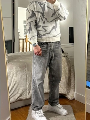 Segno - Stickad tröja med grafiskt mönster - Snygg stickad tröja i grått och vitt med ett abstrakt grafiskt mönster. Tröjan har rund halsringning, ribbade muddar och avslappnad passform. Perfekt för dig som gillar en modern och trendig stil. Materialet ser ut att vara mjukt och bekvämt.