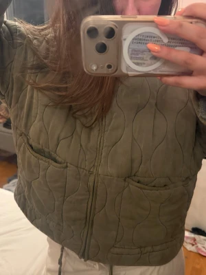 Olivgrön quiltad cardiganjacka - Quiltad cardiganjacka i olivgrönt med dragkedja framtill och två stora fickor. Jackan har ett vågigt mönster i tyget och en avslappnad passform. Perfekt för lager-på-lager och ger en cool, trendig vibe. från zara och i s! använd fåtal gånger