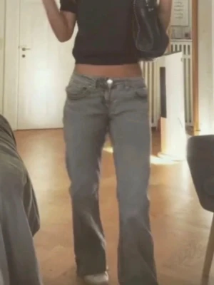 Lågmidjade bootcut jeans blå - Säljer ett par blå lågmidjade bootcut jeans med klassisk femficksdesign. Jeansen har en avslappnad passform och är perfekta för en trendig och avslappnad stil. Materialet är jeans i bomull och de har en snygg vintage vibe.