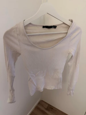 Ljusribbad långärmad topp 157 - Säljer en ljus, ribbad långärmad topp från 157. Toppen har en rundad halsringning och är figurnära i modellen. Perfekt att styla med jeans eller kjol för en clean och enkel look.