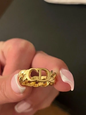 Dior ring dam - Säljer dior dam ring som är nästan ny i skick, Inga skador eller liknande. Kvitto, bag, dustbag samt papper medföljer. Storlek L men passar även M. Kan gå ner i pris vid snabb affär.