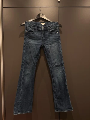 Blå bootcut jeans med fickdetaljer - Snygga blå bootcut lågmidjade jeans med dekorativa fickor bak. Från Gina tricot Young i stl 158