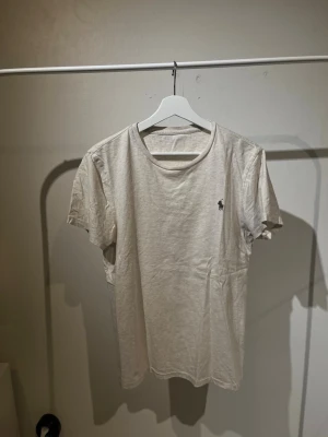 Vit t-shirt från Ralph Lauren - Klassisk vit t-shirt från Ralph Lauren med rund halsringning och liten broderad logga på bröstet. T-shirten är i mjuk bomull och har en enkel, stilren design som passar till det mesta. S/M