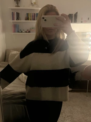 Randig stickad tröja - Säljer en olite versized stickad tröja med breda svarta och cremevita ränder. Tröjan har långa ärmar och en avslappnad passform, perfekt för en chill och trendig look. Från Hm i storlek S