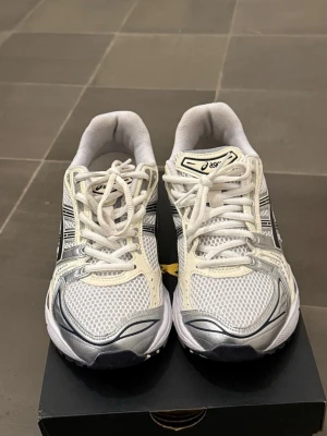  Asics sneakers - Säljer ett par supersnygga Asics gel-kayano 14 "white midnight" ✨  ✨Färg: Vit mesh-bas med metallic silver overlays, svarta tiger stripes och mörk accent som ger en lyxig, clean och premiumkänsla  ✨Storlek: 39.5  ✨Skick: Väldigt bra begagnat skick – endast använt skorna en gång   ✨Komfort: Legendarisk GEL-dämpning i häl och framfot → känns som att gå på moln! Perfekta för både vardag, promenader, gym eller streetstyle 