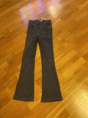Mörkblå bootcut jeans - Säljer ett par mörk gråa bootcut jeans med klassisk femficksdesign och utsvängda ben. Jeansen har normal midja och är tillverkade i ett mjukt denimtyg som ger en skön passform. 