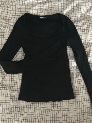 Svart ribbad långärmad topp Gina Tricot - Snygg svart ribbad topp från Gina Tricot med lång ärm och fyrkantig ringning. Figurnära passform och stretchigt material som sitter bekvämt. Perfekt att styla med jeans eller kjol för en trendig look.