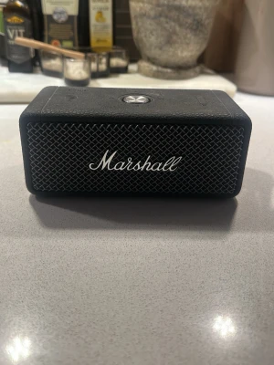 Marshall svart bärbar högtalare - Snygg bärbar högtalare från Marshall i svart med klassisk metallgallerfront och Marshall-logga. Kompakt rektangulär design med robust känsla och Bluetooth-stöd. Perfekt för att ta med sig musiken överallt och enkel att koppla till mobilen.