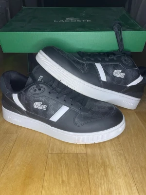 Lacoste - Snygga svarta Lacoste sneakers med vita detaljer och logga på sidan. Skorna är mycket bra skick. Köptes på footlocker som nu stängt för 1550 kr. Storlek 40,5 och säljes för 649kr. Vid frågor är d bara att skriva 😀//mvh swemarket