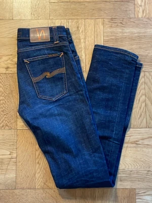  Nudie Jeans - Snygga mörkblå jeans från Nudie Jeans med klassisk femficksmodell och kontrastsömmar. Jeansen har en smal passform och är tillverkade i denim med en cool tvätt. Perfekta för dig som gillar stilrena och tidlösa jeans. Skriv om du har frågor!