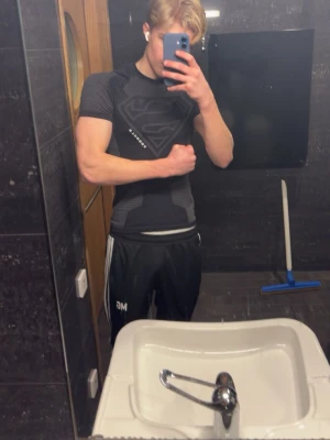 Svart Superman kompressionströja - Säljer en tight svart kompressionströja från young la med Superman-logga på bröstet. Tröjan har korta ärmar och är tillverkad i ett stretchigt funktionsmaterial som andas, perfekt för gym eller träning. Kom med bud. Priset som angetts är bara temporärt