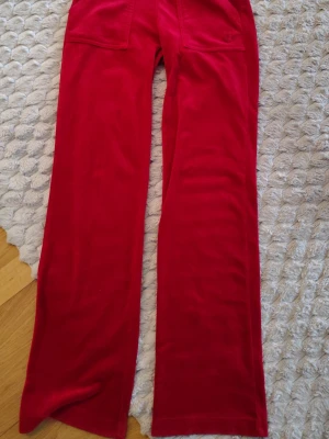 Juicy Couture byxor - Säljer ett par snygga röda mjukisbyxor i mjuk velour med raka ben och bakfickor. Från märket juicy Couture. Fint skick 