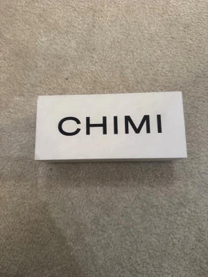 Chimi solglasögon med vit förpackning, färgen är typ onsylig/ vit och grå. Jätte bra skick, har bara använt den typ 4 gånger så skicket är typ en 9/10, box och fodral finns me! - Säljer ett par stilrena solglasögon från Chimi. De kommer i en snygg vit hård box och med en vit tygpåse för förvaring. Perfekt accessoar för att lyfta din look och skydda ögonen mot solen.