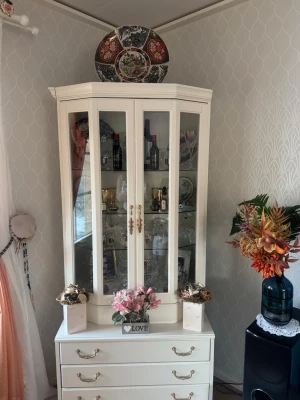 Vit vitrinskåp med lådor och glasdörrar 2 stycken - Stilrent vitrinskåp i vit färg med fyra lådor och glasdörrar. Skåpet har guldfärgade handtag och flera hyllplan för förvaring och display av porslin eller dekorationer. Passar perfekt i vardagsrum eller matsal för att visa upp fina saker. KAN ENBART HÄMTAS I STOCKHOLM! Grejerna i skåpet är ej till salu!