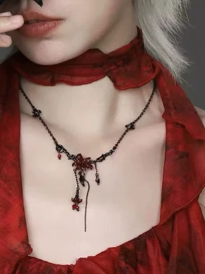 Svart halsband med örhängen med röda detaljer - Unikt halsband med svart kedja och röda blommor i metall och pärlor. Halsbandet har flera hängande detaljer och en gotisk vibe, perfekt för dig som gillar alternativ stil. De röda blommorna och små pärlor ger en cool kontrast mot den mörka metallen.