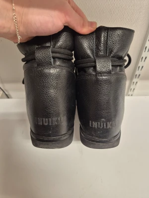 Svarta inuikkiskor - Svarta läderskor i storlek 40 från INUIKKI med kilklack. Välanvända och har försökt laga den slitna hälen med skumlappar. Innersulan var utsliten men har bytt mot äkta lamm/fårskinn (se sista bilden). Skriv vid frågor🫶
