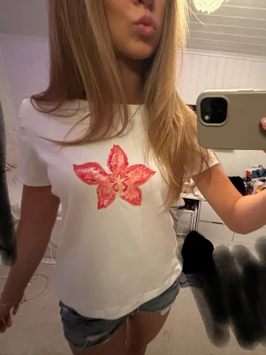 T-shirt med blomma  - Söt vit t-shirt i bomull med coralfärgad blomma tryckt🌺 köpt i costa rica på en marknad förra året, saknar lapp. Skulle säga att den är i storlek S 