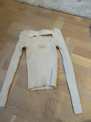 Ribbad beige topp från Zara - Säljer en ribbad beige topp från Zara i storlek M. Toppen har lång ärm, rundad halsringning och är figurnära i passformen. Materialet är mjukt och stretchigt, perfekt för att styla med jeans eller kjol. 