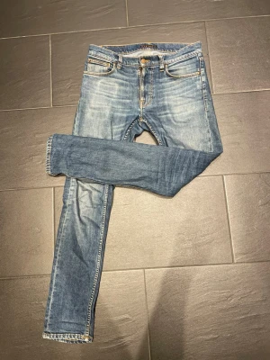 Vintadge jeans från Nudie Jeans - Säljer ett par blå slim fit jeans från Nudie Jeans med klassisk femficksmodell och snygga slitningar, sitter som w30 mer än w29. Jeansen har en något låg gren och smal passform hela vägen ner. Materialet är mjukt denim med stretch för extra komfort. Pris kan diskuteras!
