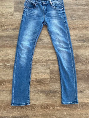 Retour jeans  - Snygga blå skinny jeans från Retour med klassisk femficksmodell och lätt slitna detaljer. Jeansen är tillverkade i en stretchig mix av bomull, polyester och elastan för skön passform. Perfekta för dig som gillar en smal siluett och vill ha ett par stilrena jeans.