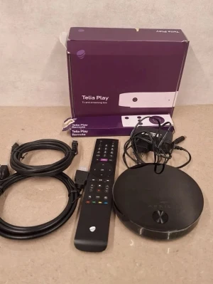 Telia Play TV-box med fjärrkontroll - Telia Play TV och streaming box i svart rund design, med tillhörande fjärrkontroll och strömadapter. Perfekt för att streama serier och filmer direkt till din TV. Allt levereras i originalkartong med Telia-logga. (Obs ingår ingen hdmi sladd)