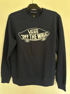 Svart sweatshirt från Vans - Cool marinblå sweatshirt från Vans med det klassiska 'Off The Wall'-trycket i vitt på bröstet. Tröjan har rund halsringning, långa ärmar och ribbade muddar. Perfekt för en avslappnad streetwear-look. Oanvänd, aldrig tvättad – i nyskick. OBS! Står storlek small på den. Prislapp/ tagg SAKNAS! 