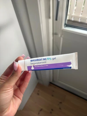 Basiron AC 5% gel mot akne - Basiron AC 5% gel är en vit tub med lila detaljer, innehållande bensoylperoxid för behandling av akne. Tuben är tillverkad i plast och har en praktisk skruvkork. Perfekt för dig som vill behandla finnar och orenheter i ansiktet.