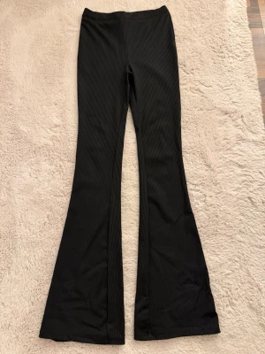 Svarta ribbade bootcut leggings - Säljer ett par svarta ribbade leggings från Lager 157 - bootcut-modell. De har hög midja och stretchigt material som sitter snyggt. Perfekta för dig som gillar en trendig och bekväm stil med lite utsvängda ben. Helt oanvända 