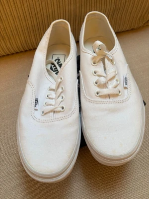Vita Vans Authentic sneakers - Klassiska vita Vans Authentic sneakers i canvas med lågt skaft och vit gummisula. Skorna har vita snören och diskreta Vans-loggor på sidan. Perfekta för en clean och enkel stil. köparen betalar frakten. 