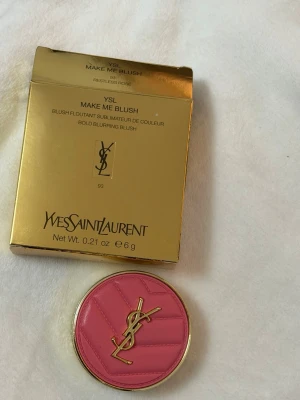 YSL Make Me Blush Rouge - Lyxigt rouge från Yves Saint Laurent i nyansen Restless Rose. Kommer i en rund, guldig dosa med rosa lock och YSL-logga i metall. Rouget har en varm rosatonad färg med lätt skimmer och präglad logotyp i pudret. Förpackningen är elegant och exklusiv.