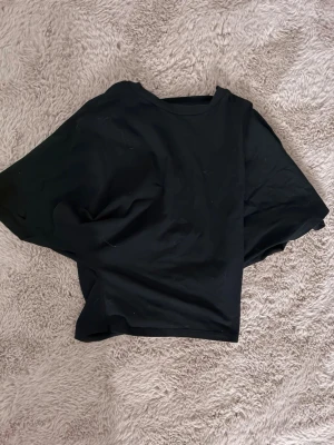 Svart T-shirt med smalare midja - En enkel svart t-shirt med rund hals, smal midja och korta ärmar. Perfekt till jeans eller shorts och funkar året runt. Tillverkad i mjuk bomull för skön känsla och avslappnad passform.
