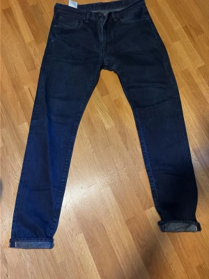 Levis selvedge jeans - Säljer ett par mörkblå selvedge jeans från levis med rak passform och klassisk femficksdesign. Jeansen har uppvikta benslut och är tillverkade i denim. Perfekta för en avslappnad och stilren look. Är selvedge så har potential för 