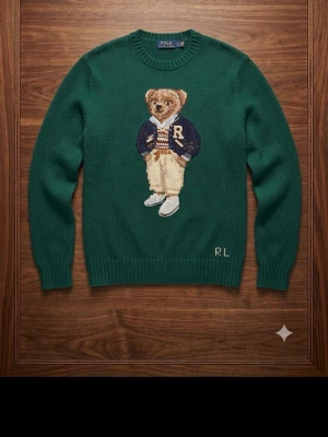 Polo Ralph Lauren Stickad Tröja – Polo Bear  - Säljer en exklusiv mörkgrön stickad tröja från Polo Ralph Lauren i storlek M med den ikoniska Polo Bear på framsidan. Tröjan är i nyskick, endast använd ett fåtal gånger och har inga fläckar, hål eller andra skador.  • Märke: Polo Ralph Lauren • Storlek: M • Färg: Mörkgrön • Motiv: Klassisk Polo Bear • Skick: Som ny, använd fåtal gånger  📦 Jag skickar samma dag eller senast dagen efter köp för en snabb och smidig affär!