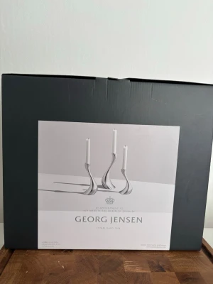 Georg Jensen ljusstakar i rostfritt stål - Säljer ett set med tre eleganta ljusstakar från Georg Jensen i blankt rostfritt stål. Ljusstakarna har en modern, böjd form som ger ett stilrent intryck och passar perfekt som dekoration i hemmet. Levereras i originalförpackning.