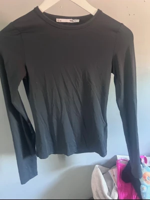 Blå långärmad topp - En enkel blå långärmad topp med rund halsringning. Perfekt att styla till jeans eller kjol för en clean och stilren look. Materialet känns mjukt och stretchigt, vilket gör den bekväm att bära hela dagen.