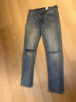 Blå slitna jeans med hål på knäna - Snygga blå jeans i klassisk femficksmodell med raka ben och slitningar över båda knäna. Jeansen har en tvättad look och är gjorda i denim, vilket ger en avslappnad och trendig vibe. Perfekta för dig som gillar en lite mer edgy stil, 30kr+40kr frakt 📦 paket: medium size