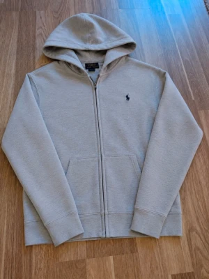 Grå zip hoodie från Polo Ralph Lauren - Tjena, jag säljer en riktigt snygg Ralph Lauren zip hoodie☺️ Den är i bra skick men har några skador, därav priset😁 Den är självklart äkta✅ Skicka om du har några frågor och kom gärna med bud😄