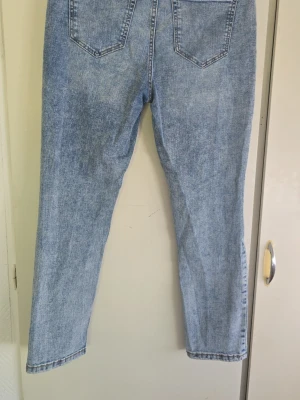 Ljusblå raka jeans - Säljer ett par ljusblå jeans med rak passform och klassiska bakfickor. Jeansen har en tidlös tvätt och är tillverkade i denim. Perfekta för dig som gillar en avslappnad och enkel stil.