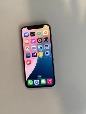 Lila iPhone med dubbla kameror - iPhone 12 mini med 64 GB lagringsutrymme. Telefonen har en batterikapacitet på 77%. Fin skick Funkar bra Bara mobilen