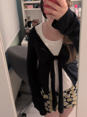 Mörkblå topp med knyt - Mörkblå topp i mjukt material med långa ärmar och knyt framtill. Perfekt att bära över ett linne eller t-shirt för en chill och avslappnad look. Enkel och stilren design som funkar året runt.