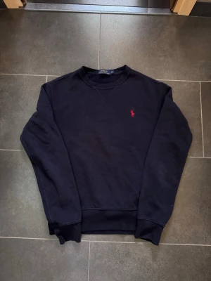 Sweatshirt från Polo Ralph Lauren -  Mörkblå sweatshirt från Polo Ralph Lauren. Ny pris runt 1299. Storlek XS