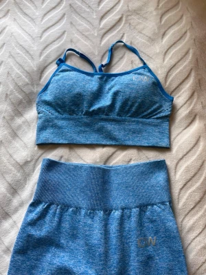 Blått träningsset från ICANIWILL - Snyggt blått träningsset från ICANIWILL med sport-bh och matchande tights. Setet är sömlöst med smala axelband på bh:n och hög midja på tightsen. Materialet är stretchigt och andas, perfekt för gym eller yoga. Diskret ICANIWILL-logga på både bh och tights.