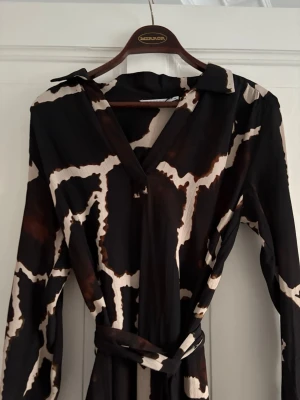 Mönstrad klänning  - En mönstrad midi klänning från Coster Copenhagen i storlek S. Den har även snygga detaljer på ärmarna och ett avtagbart och justerbart skärp i midjan. 