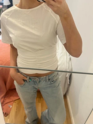 Vit topp! - Säljer en vit croppad t-shirt med korta ärmar och snygg snörning i midjan som ger en tight passform. 