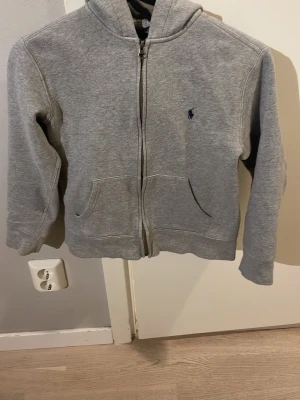 Grå Ralph lauren zip hoodie i storlek m (10-12) - Säljer denna Ralph Lauren zip hoodie i grå. Storleken är M (10-12). Är i nytt skick och säljer eftersom den är allt för liten för mig. Hör av dig vid fler frågor. Mvh Philip 