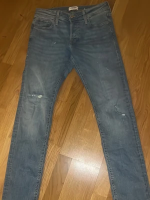 Blå slitna slim Glenn 30/32 - Säljer ett par blå skinny jeans med slitningar och lätt tvättad look. Jeansen har klassisk femficksdesign, normal midja och dragkedjegylf. Perfekta för en avslappnad och trendig stil. Pris kan diskuteras. Slim Glenn