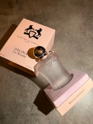 Parfums de Marly Delina La Rosée 75ml - Lyxig parfym från Parfums de Marly, Delina La Rosée, 75ml. Flaskan är frostad och ljusrosa med eleganta detaljer och silverfärgad kork. Kommer i exklusiv rosa förpackning med Royal Essence-serien. Perfekt för dig som gillar exklusiva dofter kvitto finns. Ny pris 3500!